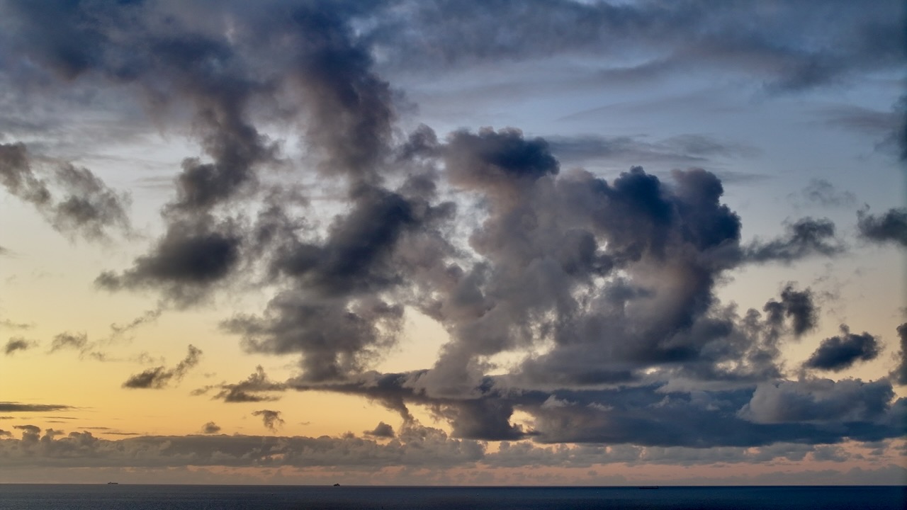 Dramatic cloud formations over a calm ocean at dawn