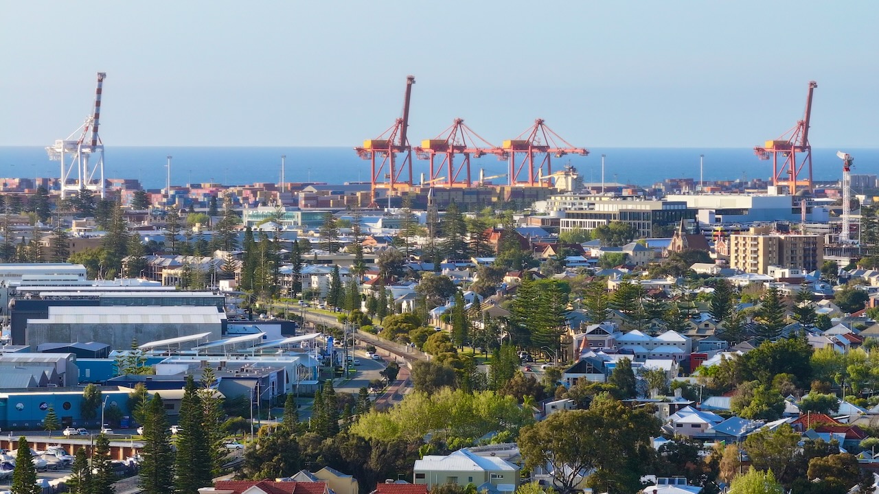 Red port gantry cranes above Fremantle rooftops